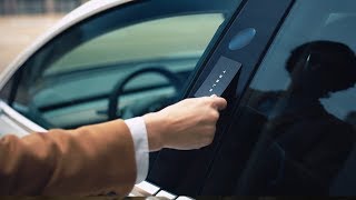 A view of a person’s hand holding a card and tapping the car’s door